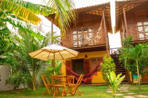 a table with an umbrella in front of a house at Pousada Dunas do Icarai in Icaraí
