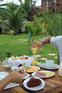 a person pouring a glass of wine on a table with food at Pousada Dunas do Icarai in Icaraí