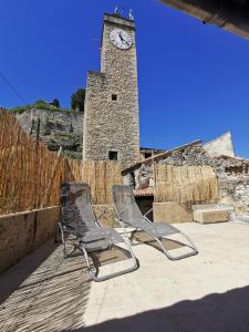 duas cadeiras sentadas em frente a uma torre do relógio em La suite du beffroi em Malaucène