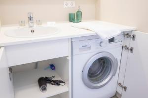 a white laundry room with a sink and a washing machine at Modern City Hideaway Graz in Graz