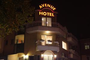 a hotel with a sign on top of it at night at Avenue in Shumen