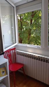 a red chair sitting in front of a window at Colors of Cvjetno Apartment in Zagreb