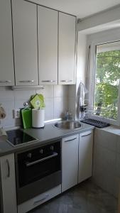 a kitchen with white cabinets and a sink and a window at Colors of Cvjetno Apartment in Zagreb