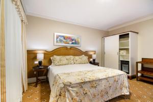 1 dormitorio con 1 cama, 2 mesas y armario en Pousada Italia Eleganza, en Campos do Jordão