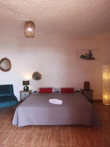 a bedroom with a bed and a blue chair at Suite Zen y Cueva Refugio in Tenteniguada