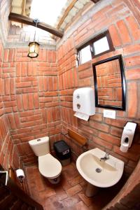 a brick bathroom with a toilet and a sink at Estancia Lolita (Cabaña en Cuenca) in Cuenca