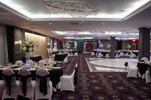 un salón de banquetes con mesas y sillas y una lámpara de araña en The Royal Regency Hotel en Yonkers