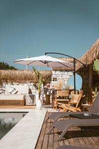 een patio met stoelen en een parasol naast een zwembad bij Voger Alaçatı Silence in Alacati