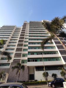un edificio alto con palmeras delante en Suite Riverfront Puerto Santa Ana, en Guayaquil