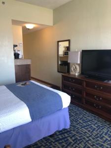 um quarto de hotel com uma cama e uma televisão de ecrã plano em Capes Hotel em Virginia Beach