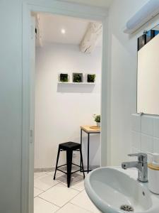 a white bathroom with a sink and a stool at BE MY APPARTS, Studio de charme "LE COSY", DOUAI, Coeur de ville in Douai