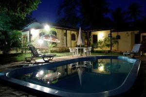 una piscina di fronte a una casa di notte di Pousada restaurante Vila Imbassai a Imbassai