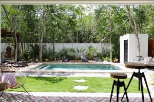 a swimming pool in a backyard with chairs and a table at Lumina at Looltum Tulum in Tulum