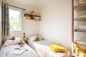 two twin beds in a room with a window at Camping La Baie des Voiles in Porto-Vecchio