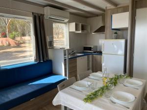 a dining room with a table and a kitchen at Camping La Baie des Voiles in Porto-Vecchio