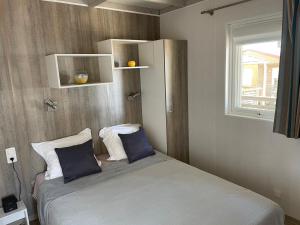 a bedroom with a bed with two pillows and a window at Camping La Baie des Voiles in Porto-Vecchio