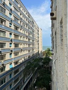 een hoog gebouw met palmbomen ervoor bij Lindo Apartamento em Frente a Praia - Santos in Santos