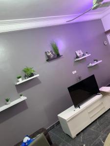salon z telewizorem na fioletowej ścianie w obiekcie Peaceful Stay 1SR w mieście Kotonu