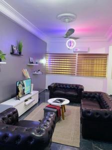 sala de estar con 2 sofás de cuero y TV en Peaceful Stay 1SR en Cotonú