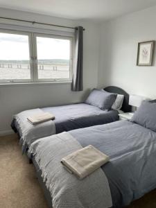 a bedroom with two beds and a window with a beach at Lux Waterfront 2 bed Apt, V&A 10min walk, St Andrew's Golf 25min drive in Dundee