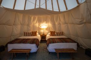 a room with two beds in a tent at Dreamcatcher Tipi Hotel in Gardiner