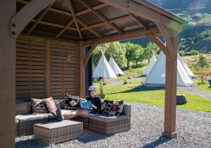 a woman sitting on a couch under a gazebo at Dreamcatcher Tipi Hotel in Gardiner