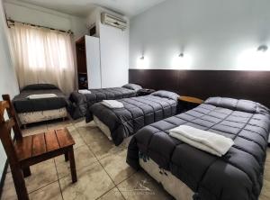 Habitación con 3 camas, silla y mesa. en Hotel Estrella Andina en San Juan