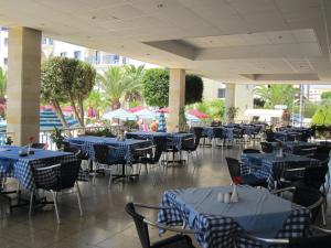 a restaurant with blue tables and chairs and a pool at Crown Resorts Elamaris in Protaras