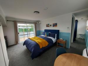 a bedroom with a blue and yellow bed and a table at DuxHouse BnB in Taihape