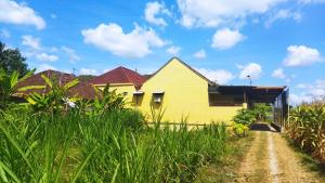 ein gelbes Haus mit roten Dächern und einer unbefestigten Straße in der Unterkunft Bougenville Homestay in Lembar