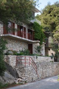 kamienny dom z kamienną ścianą i czerwoną poręczą w obiekcie Apartments by the sea Sobra, Mljet - 4898 w mieście Babino Polje