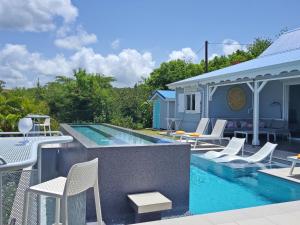 een zwembad met witte stoelen en een huis bij Blue Haven Villas Guadeloupe Villa Blue Star in Bouillante