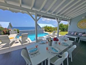een eettafel op een patio met uitzicht op de oceaan bij Blue Haven Villas Guadeloupe Villa Blue Star in Bouillante