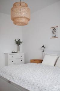 a white bedroom with a bed and a lamp at Bon Repos Apartmán in Donovaly