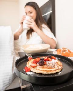 una mujer sentada en una mesa con un plato de panqueques con fruta en Sendero Hotel, en Actopan