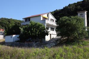 a white house on the side of a hill at Apartments with parking space Supetarska Draga - Donja, Rab - 4991 in Rab