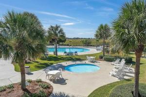 a pool with palm trees and chairs in a yard at St Helena Island Retreat with Deck Walk to Beach in Oceanmarsh Subdivision
