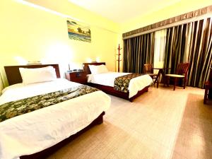 a hotel room with two beds and a table at Serenti Hotel Saipan in Garapan