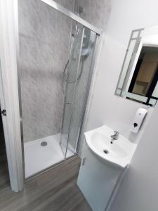 La salle de bains blanche est pourvue d'une douche et d'un lavabo. dans l'établissement The Oak Studio -Self contained one bed studio flat, à Oxford
