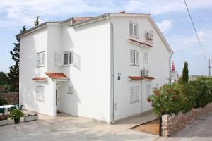 ein weißes Apartmenthaus mit einem Innenhof in der Unterkunft Apartments with parking spaces Barbat, Rab - 4962 in Rab