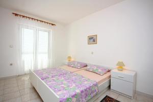 ein weißes Schlafzimmer mit einem Bett und einem Fenster in der Unterkunft Apartments with parking spaces Barbat, Rab - 4962 in Rab