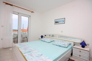 ein weißes Schlafzimmer mit einem Bett und einem Fenster in der Unterkunft Apartments with parking spaces Barbat, Rab - 4962 in Rab