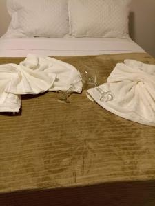 Una cama con dos toallas y un vaso. en Chalés por do sol, en Pirenópolis