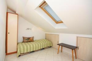 a small bedroom with a bed and a table at Apartments by the sea Barbat, Rab - 5005 in Barbat na Rabu