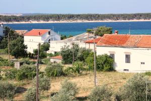 a white house with red roofs next to the water at Apartments by the sea Barbat, Rab - 5005 in Barbat na Rabu