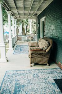 une chaise en osier assise sur la terrasse couverte d'une maison dans l'établissement Benn Conger Inn, à Groton