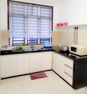 a kitchen with white cabinets and a microwave at Desaru M'Cozy,12pax,Waterpark,BBQ,WIFI in Bandar Penawar