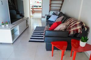 un soggiorno con un divano nero e una TV di Casa na Praia dos Carneiros/PE. Cond. Village IV. a Tamandaré