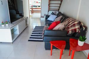 a living room with a black couch and a tv at Casa na Praia dos Carneiros/PE. Cond. Village IV. in Tamandaré