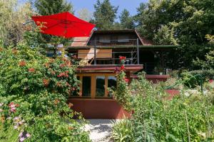 uma casa com um guarda-sol vermelho num jardim em Cottage Veronika em Velika Gorica